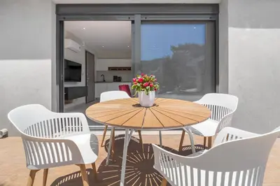 a table with white chairs and a vase of flowers at Greek Dream Homes Thimari in Sounio