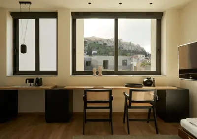 a kitchen with a desk and two windows with chairs at Athens Woo Suites in Athens
