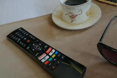 a remote control and a cup of coffee on a table at AthINN Residence in Athens