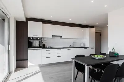 a kitchen with white cabinets and a black table at 2BDR Athens Riviera Sea View Apartment by The Olon in Athens