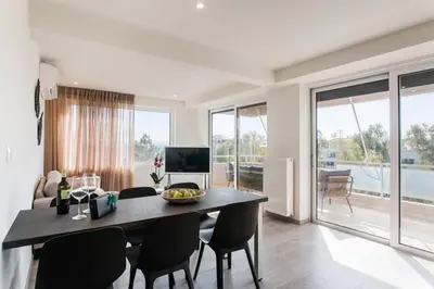 a dining room with a table and chairs and a television at 2BDR Athens Riviera Sea View Apartment by The Olon in Athens