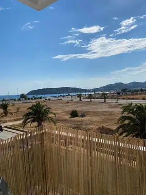 a fence in front of a beach with palm trees at Christy's House Anavissos / Ανάβυσσος in Anavissos