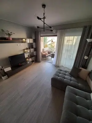 a living room with a couch and a television at Lovely Faliro Apartment next to the sea. in Athens