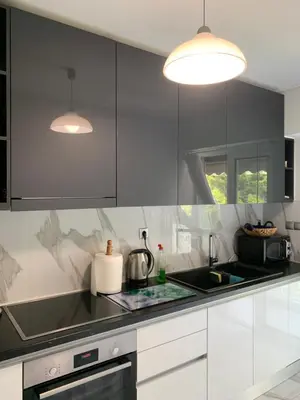 a kitchen with black and white cabinets and a sink at Lovely Faliro Apartment next to the sea. in Athens