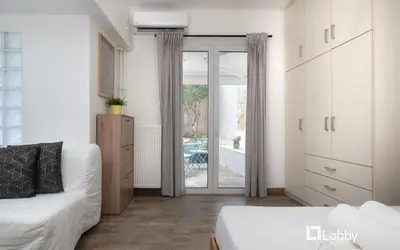 a white room with a bed and a sliding glass door at Embassy Studio in Athens