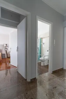 a white room with a door and a bathroom at Ioanna's Hellenic Hospitality in Athens