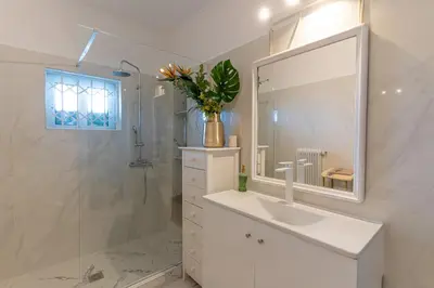 a white bathroom with a sink and a mirror at Ioanna's Hellenic Hospitality in Athens