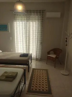 a bedroom with two beds and a chair and a window at Katerina summerhouse in Dhaskalión