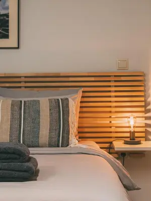 a bed with a wooden headboard and a lamp on a table at Studio Krinon - Paleo Psychiko in Athens