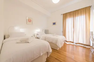 two beds in a white room with a window at Luxury Penthouse in Kolonaki with view in Athens