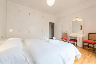 a white bedroom with two beds and two red chairs at Luxury Penthouse in Kolonaki with view in Athens