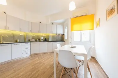 a kitchen with white cabinets and a white table and chairs at Luxury Penthouse in Kolonaki with view in Athens