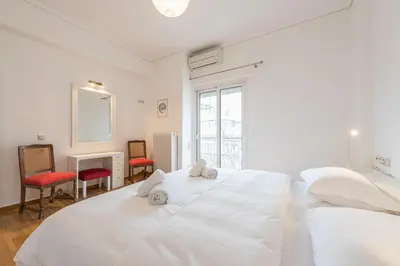 a white bedroom with a large white bed and two chairs at Luxury Penthouse in Kolonaki with view in Athens