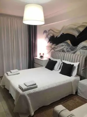 a bedroom with a large white bed with a painting on the wall at The excellent home in Athens