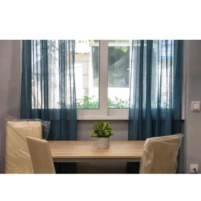 a table with chairs and a window with blue curtains at Alley's house Athens in Athens