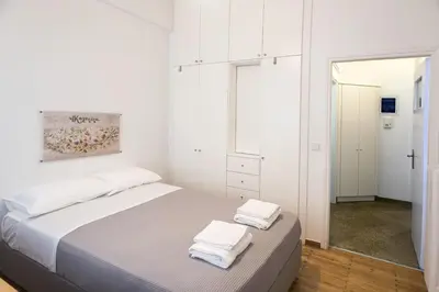 a white bedroom with a bed with two towels on it at Colourful apartment under the Acropolis in Athens
