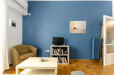 a living room with a blue wall and a chair and a table at Colourful apartment under the Acropolis in Athens