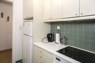 a kitchen with white cabinets and a green tiled wall at Colourful apartment under the Acropolis in Athens