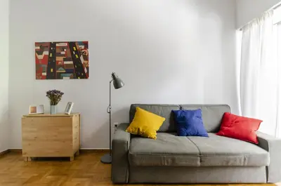 a living room with a gray couch with colorful pillows at Colourful apartment under the Acropolis in Athens