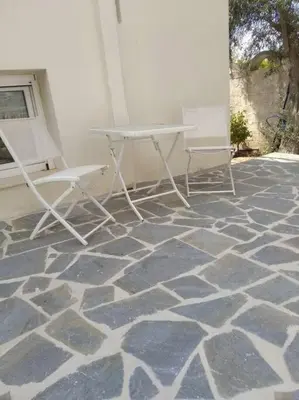 two chairs and a table on a stone floor at Cozy villa Vita Lagonisi in Kalívia Thorikoú