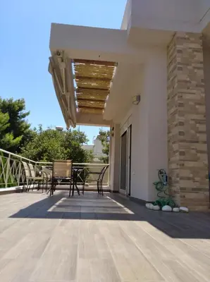 a patio with a table and chairs on a balcony at Cozy villa Vita Lagonisi in Kalívia Thorikoú