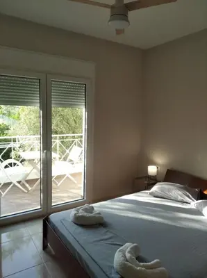 a bedroom with a bed and a balcony with a patio at Cozy villa Vita Lagonisi in Kalívia Thorikoú