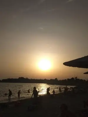 a group of people on the beach at sunset at Cozy villa Vita Lagonisi in Kalívia Thorikoú