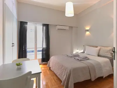 a bedroom with a bed and a table and a desk at Homy Pagrati flat 100 Mbps, 12' to Panathenaic Stadium, 5' to Metro in Athens