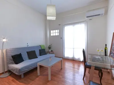 a living room with a blue couch and a table at Homy Pagrati flat 100 Mbps, 12' to Panathenaic Stadium, 5' to Metro in Athens