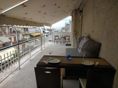 a living room with a couch and a view of a balcony at Cosy penthouse next to metro in Athens