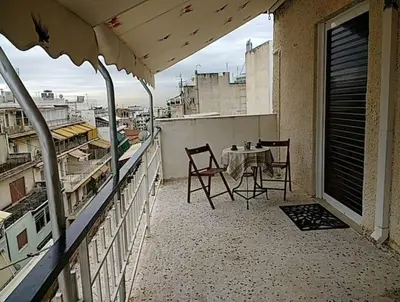 a balcony with a table and chairs on a building at Cosy penthouse next to metro in Athens