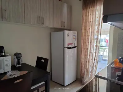 a white refrigerator in a kitchen with a table at Cosy penthouse next to metro in Athens
