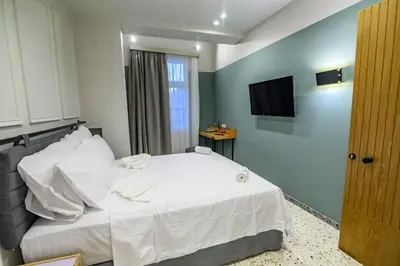 a bedroom with a white bed and a television at Belle Athenes - Luxury Rooms at Monastiraki Railway Station in Athens