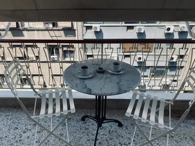 a table with two cups and two chairs on a balcony at Athens Sunnyside condo in Athens