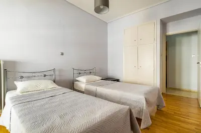 two beds in a bedroom with white walls and wood floors at Urban grey in Athens