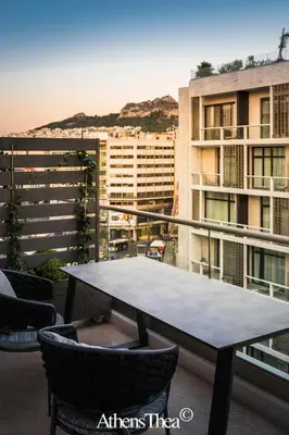 a table and chairs on a balcony with a building at AthensThea Beta Luxury Penthouse Apt in Omonia in Athens