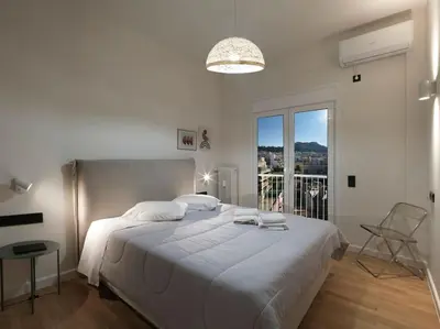a white bedroom with a large bed with a large window at Lycabettus view apartment in Athens