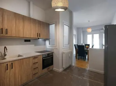 a kitchen with wooden cabinets and a black refrigerator at Lycabettus view apartment in Athens
