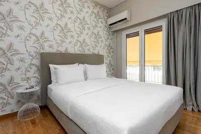 a bedroom with a white bed and a window at The Beehive Apartments in Athens