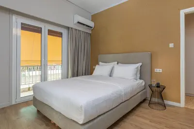 a bedroom with a bed and a large window at The Beehive Apartments in Athens