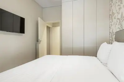 a bedroom with a white bed and a television at The Beehive Apartments in Athens