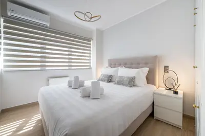 a white bedroom with a large white bed and a window at Acropolis Cozy Apartments in Athens