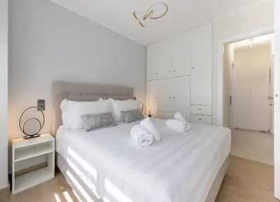 a white bedroom with a large white bed with white pillows at Acropolis Cozy Apartments in Athens