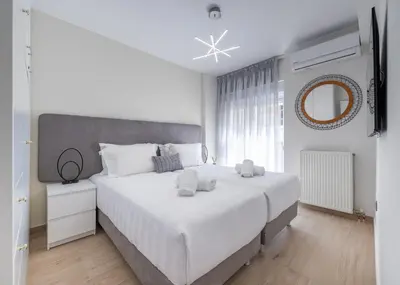 a white bedroom with a large bed and a mirror at Acropolis Cozy Apartments in Athens