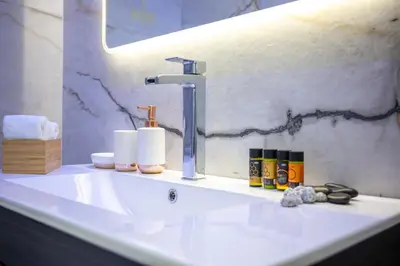a bathroom sink with a faucet and cosmetics on it at Acropolis Cozy Apartments in Athens