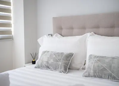 a white bed with white pillows and a headboard at Acropolis Cozy Apartments in Athens