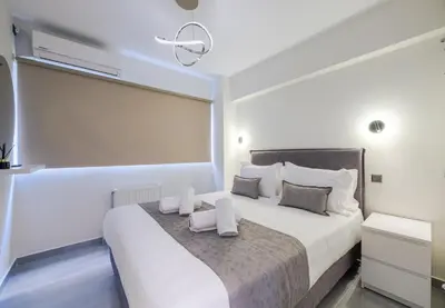 a white bedroom with a large bed with white pillows at Acropolis Cozy Apartments in Athens