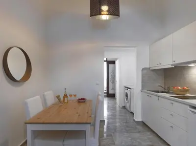 a kitchen with a wooden table and white cabinets at Elegant, affordable apartment with a fireplace in Athens