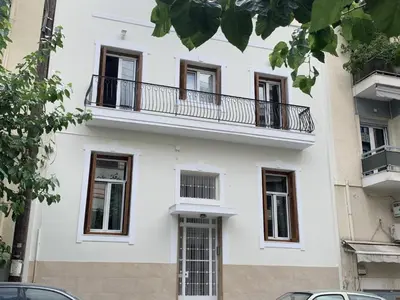 a white building with a balcony on top of it at Elegant, affordable apartment with a fireplace in Athens