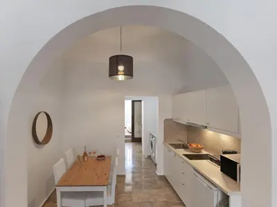a kitchen with white cabinets and a wooden table at Elegant, affordable apartment with a fireplace in Athens